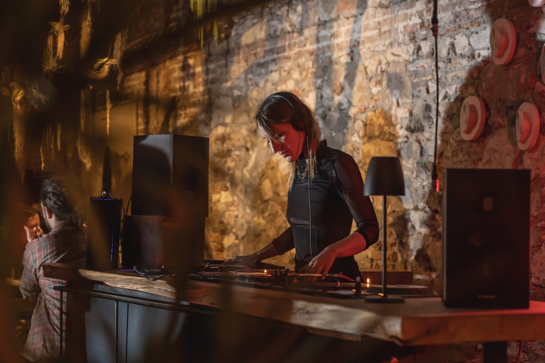 Goutier, house DJ in Barcelona, mixing in warm golden light against a stone wall